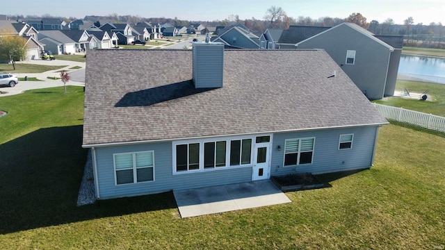 back of house featuring a patio area, a water view, and a lawn