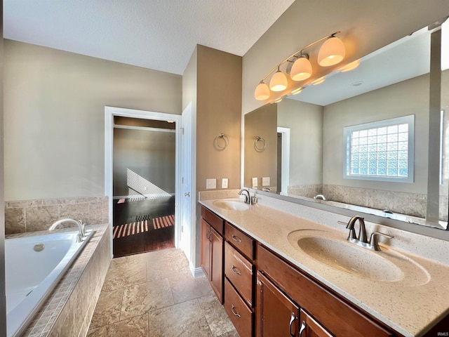 bathroom with vanity, a textured ceiling, a relaxing tiled tub, and hardwood / wood-style flooring