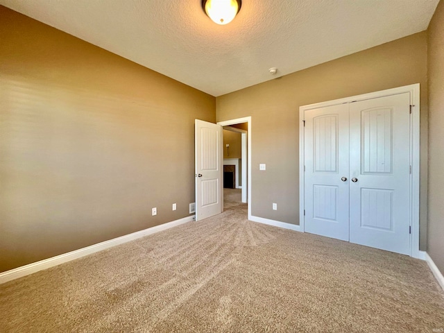 unfurnished bedroom featuring a closet, a textured ceiling, and carpet flooring