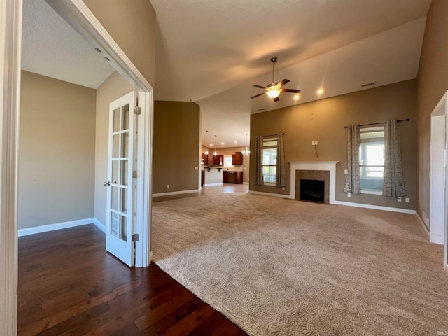 unfurnished living room featuring lofted ceiling, dark hardwood / wood-style floors, a healthy amount of sunlight, and ceiling fan