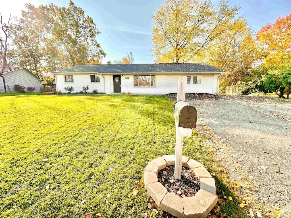 ranch-style house with an outdoor fire pit and a front lawn