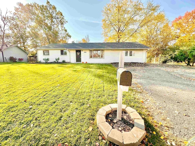 ranch-style house with an outdoor fire pit and a front lawn