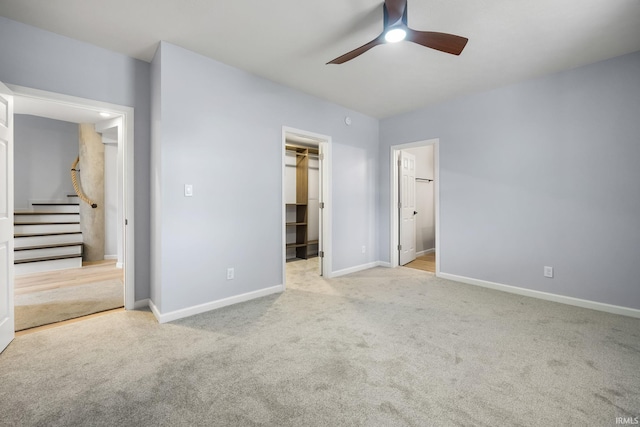 unfurnished bedroom featuring connected bathroom, a closet, a spacious closet, light colored carpet, and ceiling fan