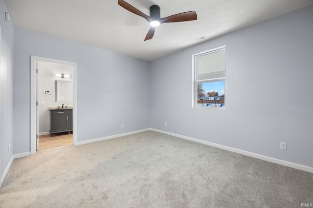 unfurnished bedroom with light carpet, ensuite bath, sink, and ceiling fan