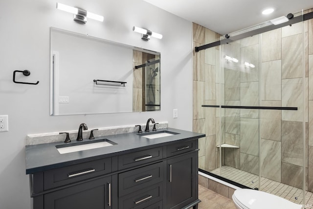 bathroom featuring vanity, toilet, and a shower with door