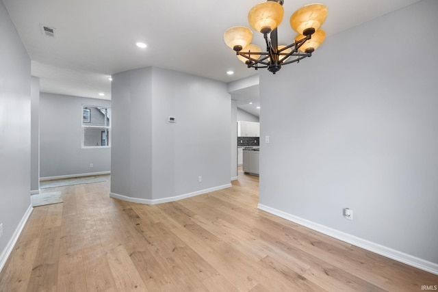 empty room with a chandelier and light wood-type flooring