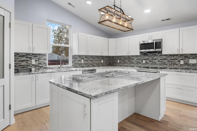 kitchen featuring appliances with stainless steel finishes, light hardwood / wood-style flooring, a kitchen island, and white cabinets