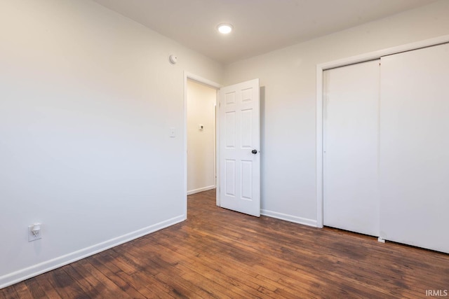 unfurnished bedroom with a closet and dark wood-type flooring