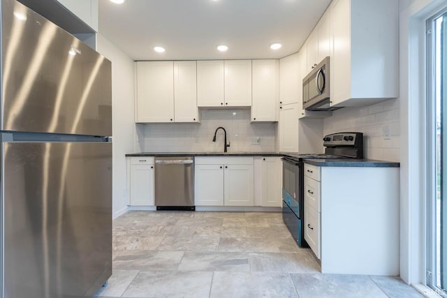 kitchen featuring appliances with stainless steel finishes, white cabinetry, tasteful backsplash, and sink