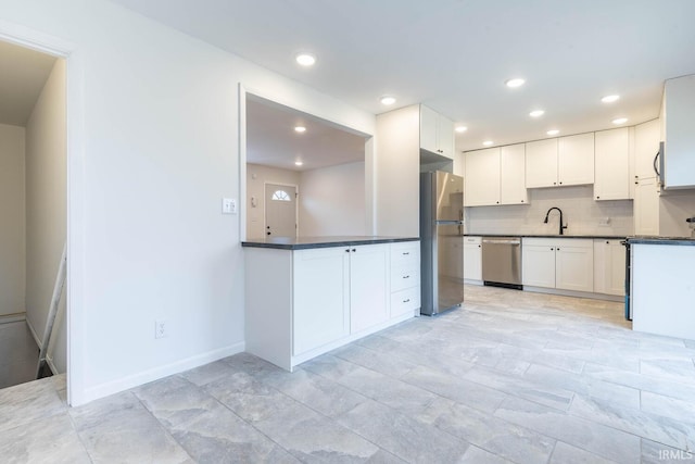 kitchen featuring sink, decorative backsplash, appliances with stainless steel finishes, and white cabinetry