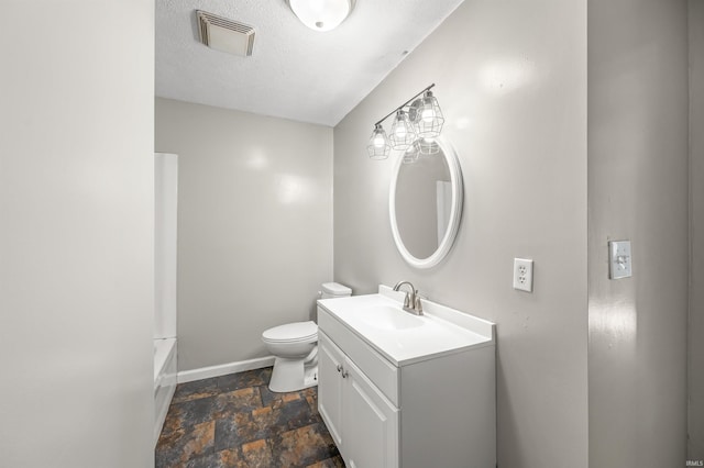 bathroom with vanity, toilet, and a textured ceiling