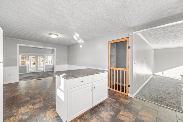 kitchen with french doors, a textured ceiling, dark carpet, and white cabinets