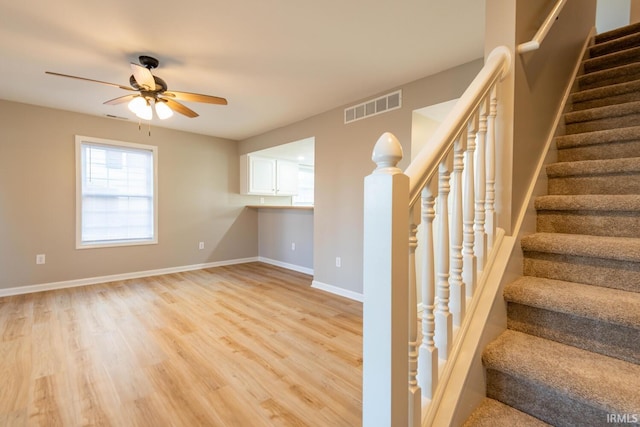 stairs featuring hardwood / wood-style flooring and ceiling fan