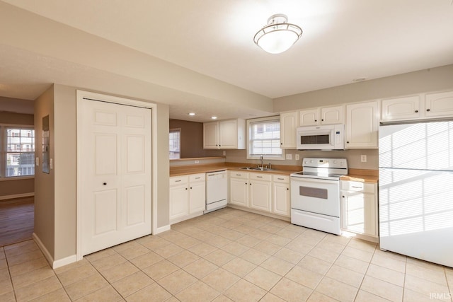 kitchen with white appliances, light tile patterned floors, white cabinetry, and sink