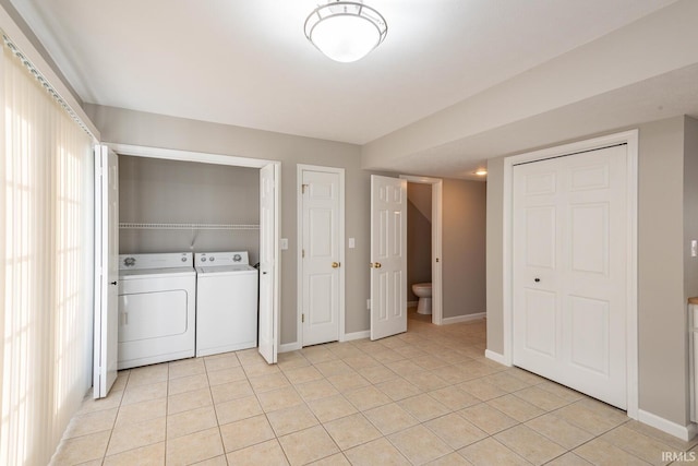 laundry area with washing machine and clothes dryer and light tile patterned floors