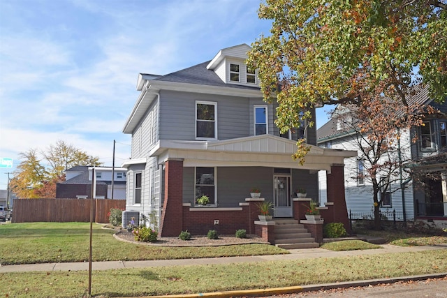 view of front facade with a front yard, covered porch, and central AC unit