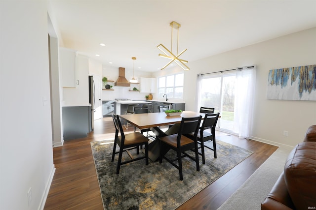 dining area with sink, dark hardwood / wood-style floors, and an inviting chandelier