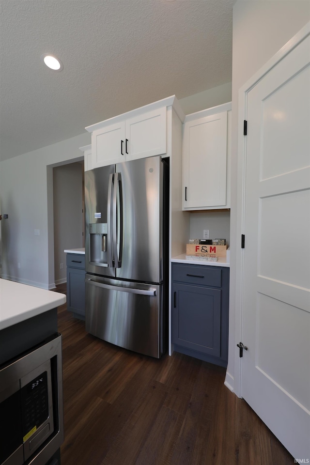 kitchen with white cabinetry, appliances with stainless steel finishes, a textured ceiling, and dark wood-type flooring