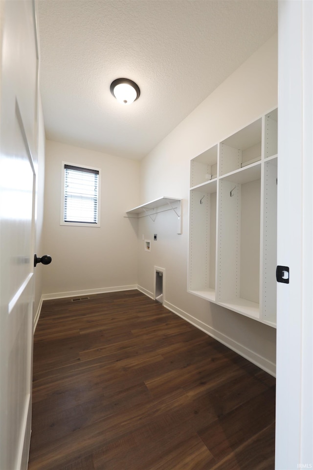 clothes washing area with hookup for an electric dryer, a textured ceiling, and dark hardwood / wood-style flooring