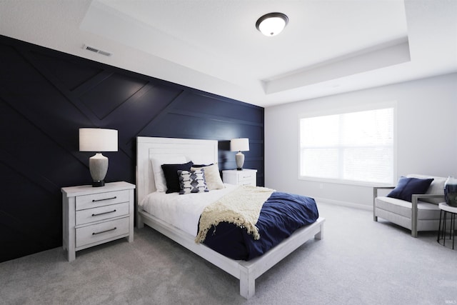 carpeted bedroom with a raised ceiling