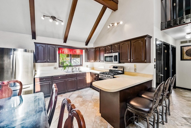 kitchen with sink, appliances with stainless steel finishes, beamed ceiling, and kitchen peninsula