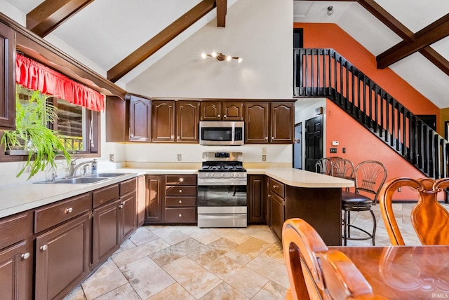 kitchen featuring sink, a kitchen bar, stainless steel appliances, beam ceiling, and high vaulted ceiling