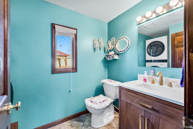 bathroom with toilet, stacked washer / dryer, and vanity