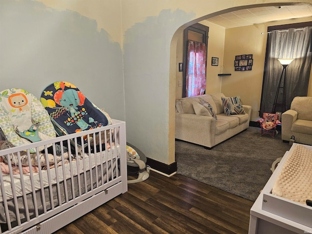 bedroom featuring a nursery area and dark wood-type flooring