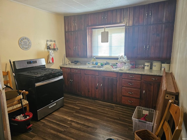 kitchen with stainless steel range with gas stovetop, dark wood-type flooring, light stone counters, and sink