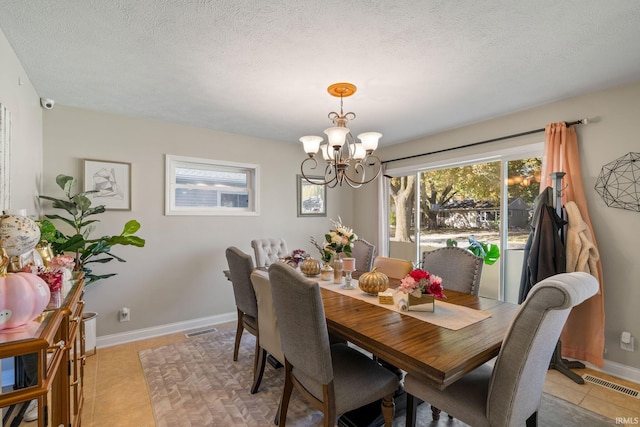 dining space featuring a notable chandelier, a textured ceiling, and light tile patterned floors