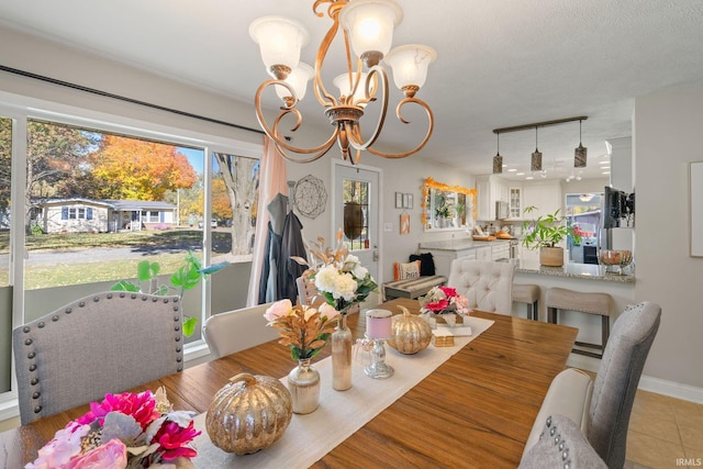 dining area with light tile patterned floors, a textured ceiling, and an inviting chandelier