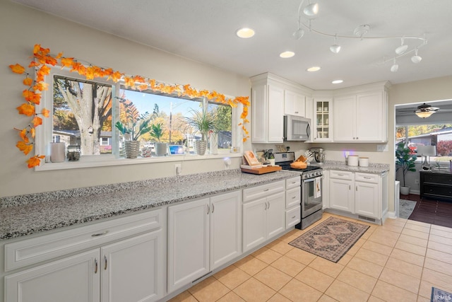 kitchen with light tile patterned floors, appliances with stainless steel finishes, white cabinets, and ceiling fan