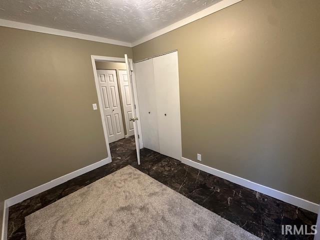 unfurnished bedroom with crown molding, dark colored carpet, a textured ceiling, and a closet