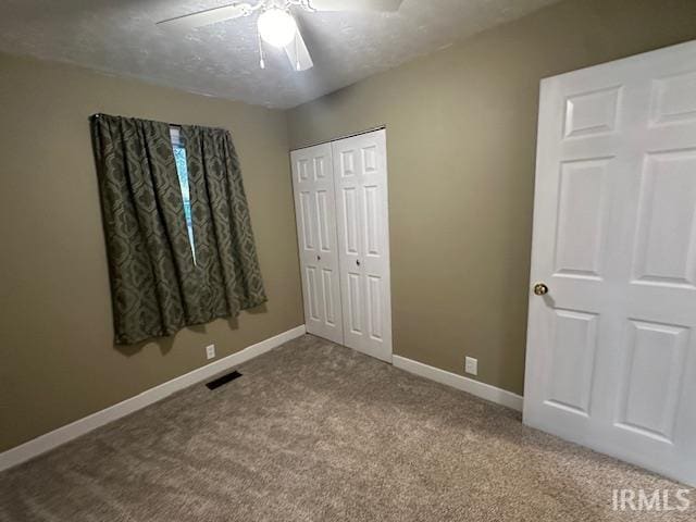 unfurnished bedroom with a textured ceiling, carpet floors, a closet, and ceiling fan