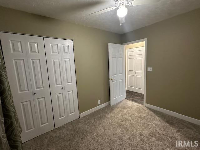 unfurnished bedroom with carpet, a textured ceiling, a closet, and ceiling fan