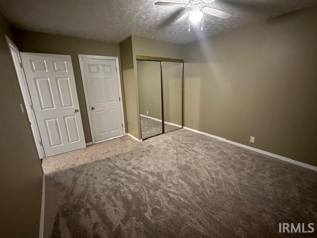 unfurnished bedroom with carpet, a textured ceiling, a closet, and ceiling fan