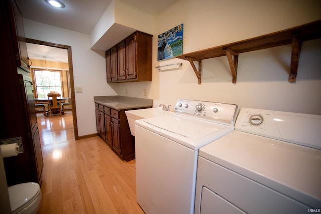 laundry area with light hardwood / wood-style flooring, sink, and separate washer and dryer