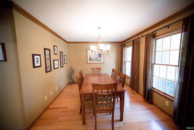 dining space with light hardwood / wood-style floors, an inviting chandelier, and ornamental molding