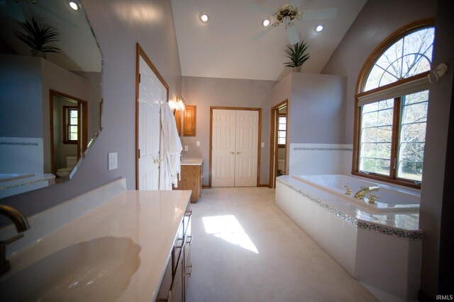 bathroom with vanity, vaulted ceiling, tiled bath, and ceiling fan