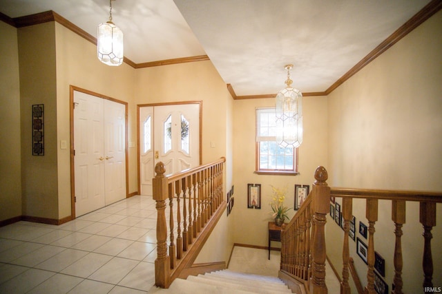 foyer with ornamental molding, a notable chandelier, and light tile patterned floors