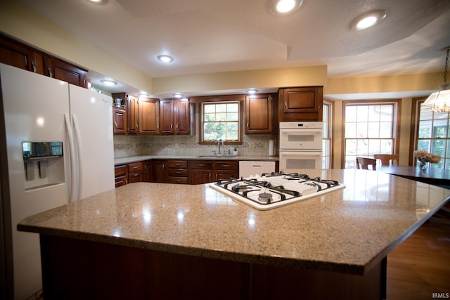 kitchen featuring white appliances, a spacious island, sink, and plenty of natural light