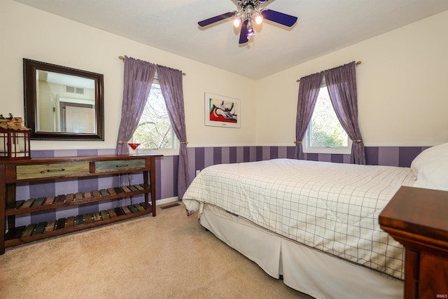 bedroom with multiple windows, light colored carpet, and ceiling fan