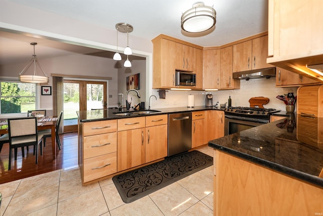 kitchen featuring hanging light fixtures, dark stone countertops, light tile patterned floors, and appliances with stainless steel finishes