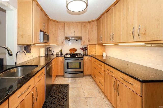 kitchen with dark stone counters, sink, tasteful backsplash, light tile patterned floors, and appliances with stainless steel finishes