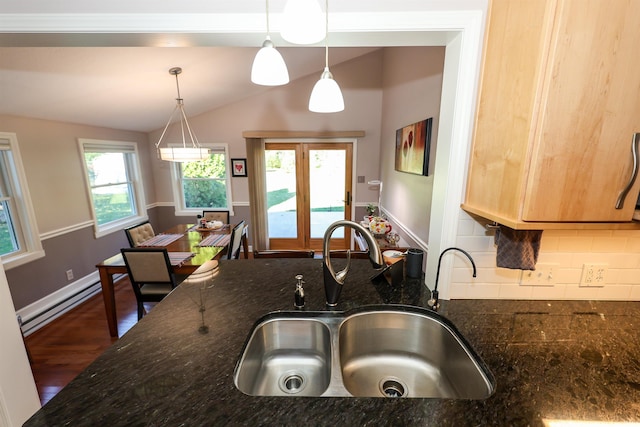 kitchen featuring lofted ceiling, dark stone counters, a wealth of natural light, hanging light fixtures, and sink