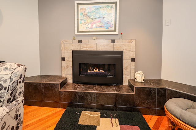 room details with a tiled fireplace and hardwood / wood-style flooring