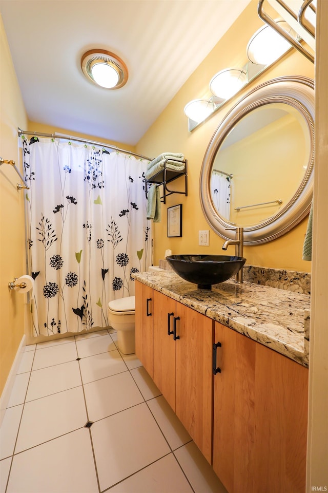 bathroom with toilet, vanity, and tile patterned floors