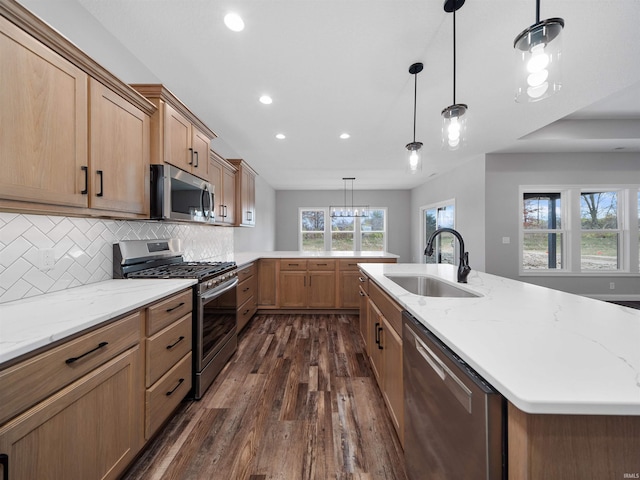 kitchen featuring tasteful backsplash, stainless steel appliances, decorative light fixtures, dark hardwood / wood-style flooring, and sink