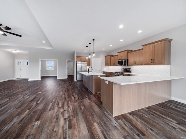 kitchen with a kitchen bar, dark hardwood / wood-style flooring, kitchen peninsula, pendant lighting, and appliances with stainless steel finishes