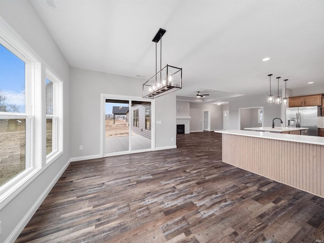 unfurnished living room with dark wood-type flooring, ceiling fan, and sink